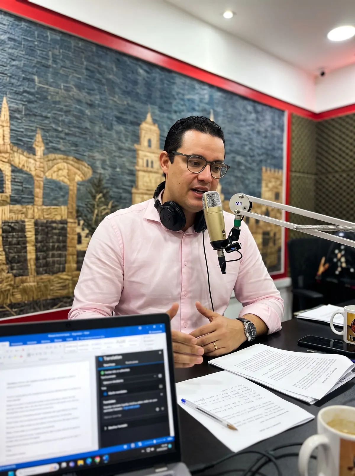 O Dr. Michel no estúdio da Rádio Sisal, de camisa rosa e fones no pescoço, falando ao microfone do De Bem com a Vida.